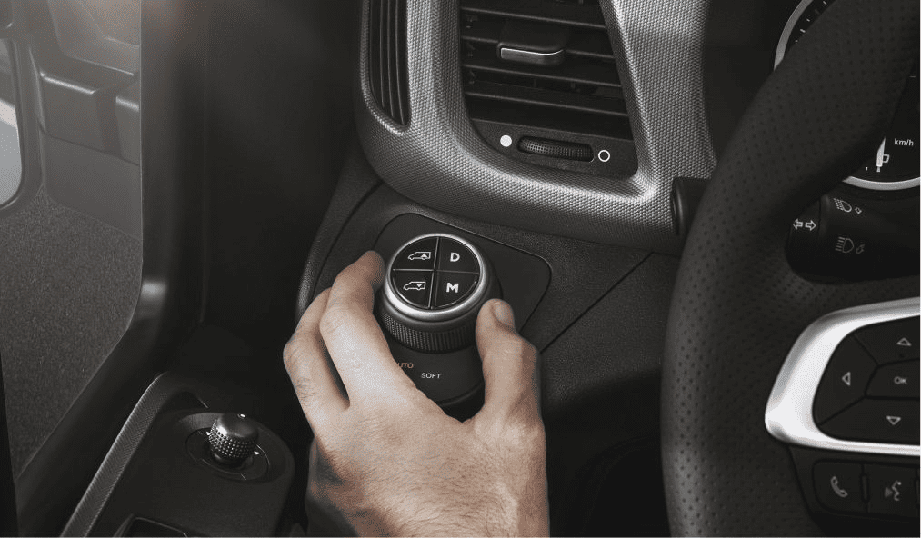 interior da cabine do E-Daily, veículo elétrico da IVECO. A mão do motorista está acessando um botão com 4 opções, ao lado do volante.